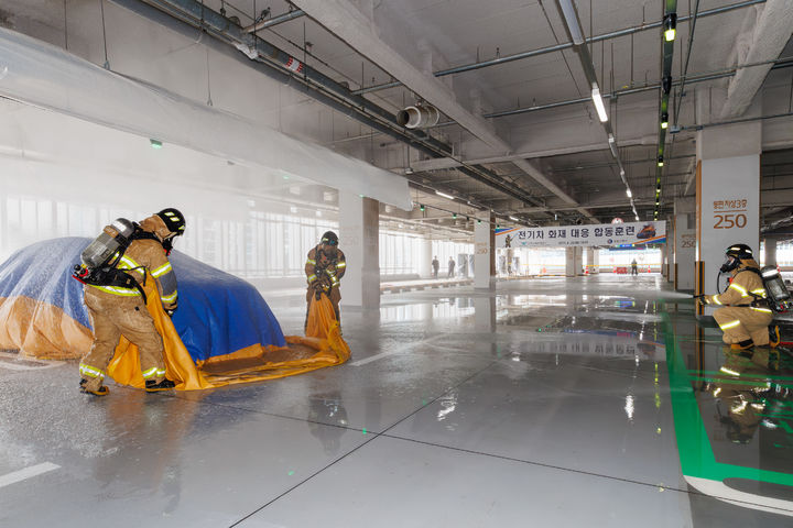 [서울=뉴시스] 인천공항공사는 지난 28일 오후 인천공항 제2여객터미널 단기주차장에서 ‘전기차 화재 대응 합동훈련’에서 공항소방대원들이 질식소화포를 이용해 전기차 화재를 진압하고 있다. 2026.04.29. (사진=인천공항공사 제공) photo@newsis.com *재판매 및 DB 금지
