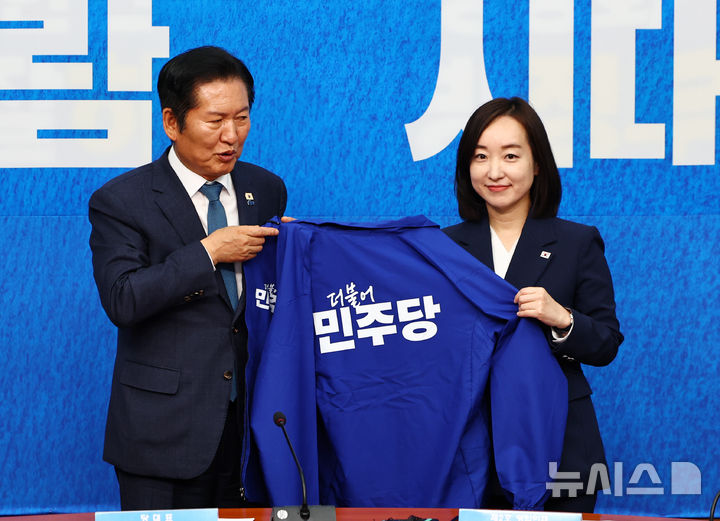 [서울=뉴시스] 김명년 기자 = 전은수 전 청와대 대변인이 29일 오전 서울 여의도 국회에서 열린 더불어민주당 인재영입식에서 정청래 대표와 당 점퍼를 들고 있다. 2026.04.29. kmn@newsis.com