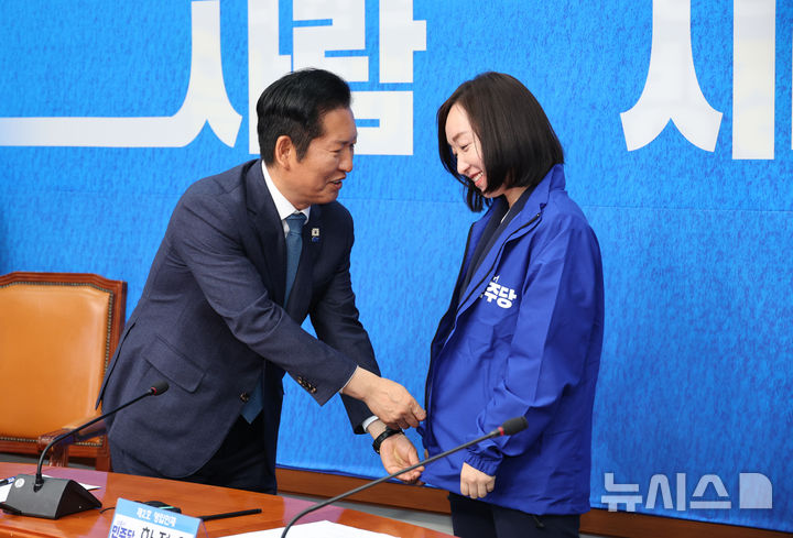 [서울=뉴시스] 김금보 기자 = 전은수 전 청와대 대변인이 29일 오전 서울 여의도 국회에서 열린 더불어민주당 2차 인재영입식에서 정청래 당대표로 부터 당점퍼를 받아 입고 있다. 2026.04.29. kgb@newsis.com