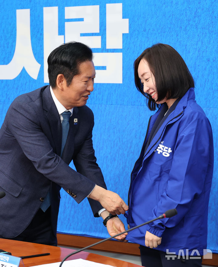 [서울=뉴시스] 김금보 기자 = 전은수 전 청와대 대변인이 29일 오전 서울 여의도 국회에서 열린 더불어민주당 2차 인재영입식에서 정청래 당대표로 부터 당점퍼를 받아 입고 있다. 2026.04.29. kgb@newsis.com