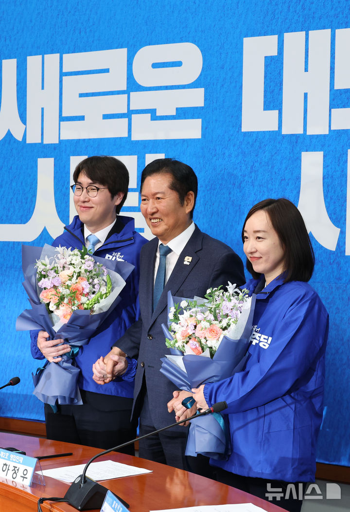 [서울=뉴시스] 김금보 기자 = 하정우(왼쪽) 전 청와대 AI미래기획수석과 전은수(오른쪽) 전 청와대 대변인이 29일 오전 서울 여의도 국회에서 열린 더불어민주당 2차 인재영입식에서 정청래 당대표로 부터 당점퍼를 받아 입고 기념촬영을 하고 있다. 2026.04.29. kgb@newsis.com