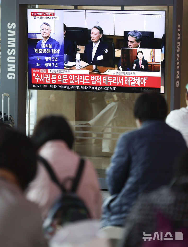 [서울=뉴시스] 조성우 기자 = 29일 오후 서울 중구 서울역 대합실에서 시민들이 체포 방해 및 국무위원 심의권 침해 혐의로 기소된 윤석열 전 대통령에 대한 2심 선고 공판 생중계를 보고 있다. 2026.04.29. xconfind@newsis.com
