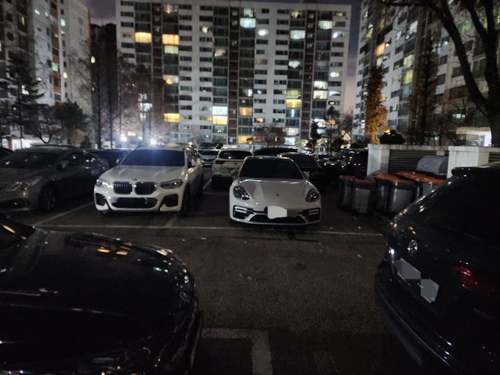 [서울=뉴시스] 30년 넘은 노후 아파트 주차장에서 한 고급 차량이 주차 구획선을 두 칸 걸친 채 세워져 있는 모습이 포착돼 논란이 일고 있다. (사진=보배드림 캡처)