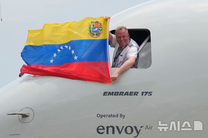 The pilot of a U.S. aircraft holds a Venezuelan flag from the cockpit window after landing at Simon Bolivar International Airport in Maiquetia, Venezuela, Thursday, April 30, 2026, as direct air service between the United States and Venezuela resumes after seven years. (AP Photo/Ariana Cubillos)