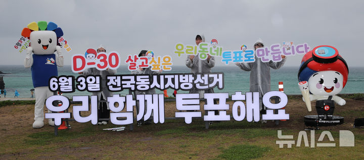[제주=뉴시스] 우장호 기자 = 6·3 지방선거가 30일 남은 3일 오전 제주시 조천읍 함덕해수욕장 내에 설치된 지방선거 홍보 조형물 앞에서 제주도선거관리위원회 관계자들이 도민과 관광객을 대상으로 투표참여를 독려하는 피켓팅 퍼포먼스를 하고 있다. 2026.05.03. woo1223@newsis.com