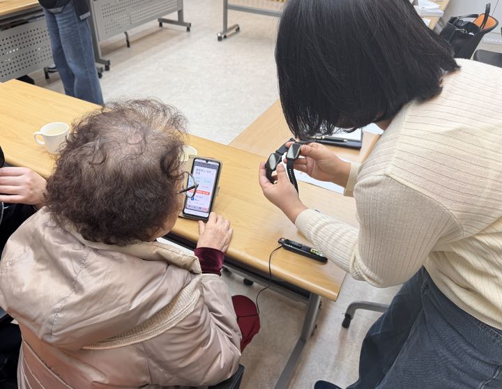 [광명=뉴시스] 광명시 치매안심센터 담당자가 '치매예방 스마트 건강케어 사업'에 참여하는 어르신에게 스마트워치 사용법을 설명하고 있다. (사진=광명시 제공) 2026.05.04. photo@newsis.com *재판매 및 DB 금지