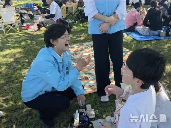[밀양=뉴시스]진보당 전희영 경남도지사 후보가 5일 밀양시 하남체육공원에서 열린 밀양 어린이 꿈나무 운동회에 참석해 한 어린이와 얘기하면서 활짝 웃고 있다.(사진=전희영후보 선거사무소 제공) 2026.05.05. photo@newsis.com