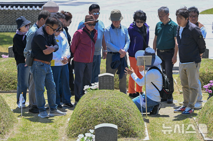 [광주=뉴시스] 이영주 기자 = 제46주기 5·18민주화운동 기념일을 8일 앞둔 10일 오전 광주 북구 운정동 국립5·18민주묘지에서 참배객들이 고(故) 문재학 열사의 묘소 앞에서 오월 해설사의 설명을 듣고 있다. 2026.05.10. leeyj2578@newsis.com