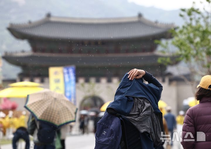 [서울=뉴시스] 김명년 기자 = 비가 내린 11일 오후 서울 종로구 광화문광장에서 시민이 겉옷으로 비를 가리며 이동하고 있다. 2026.05.11. kmn@newsis.com