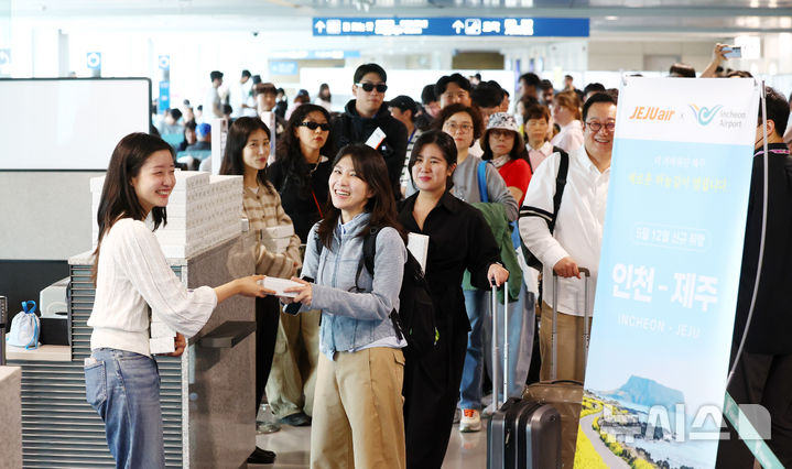 [인천공항=뉴시스] 전신 기자 = 인천-제주 국내선 직항노선이 10년 만에 운항을 재개한 12일 인천국제공항 제1여객터미널에 제주행 항공편 탑승객들이 인천공항공사 직원들로부터 운항 재개 기념품을 받고 있다. 2026.05.12. photo1006@newsis.com