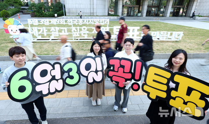 [서울=뉴시스] 전신 기자 = 13일 서울 중구 프레스센터 인근에 설치된 제9회 전국동시지방선거 홍보 조형물 앞에서 서울시선관위 직원들이 투표 참여를 독려하고 있다. 2026.05.13. photo1006@newsis.com