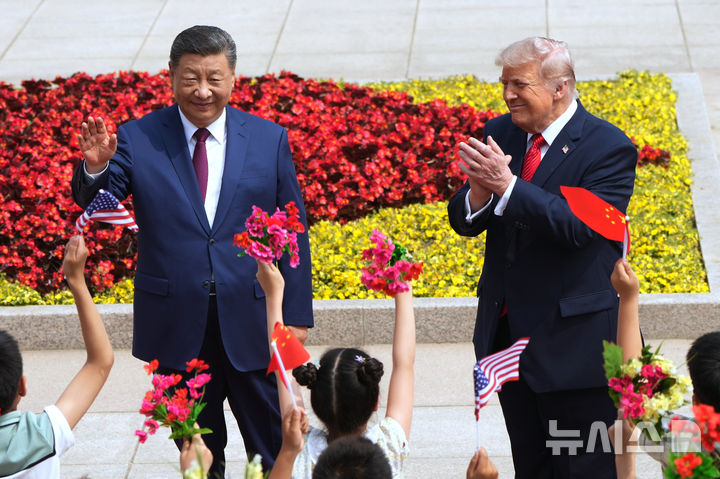 [베이징=AP/뉴시스] 도널드 트럼프(오른쪽) 미국 대통령과 시진핑 중국 국가주석이 14일(현지 시간) 중국 베이징 인민대회당에서 열린 공식 환영 행사 중 꽃다발과 국기를 들고 환영하는 어린이들에게 화답하고 있다. 2026.05.14.