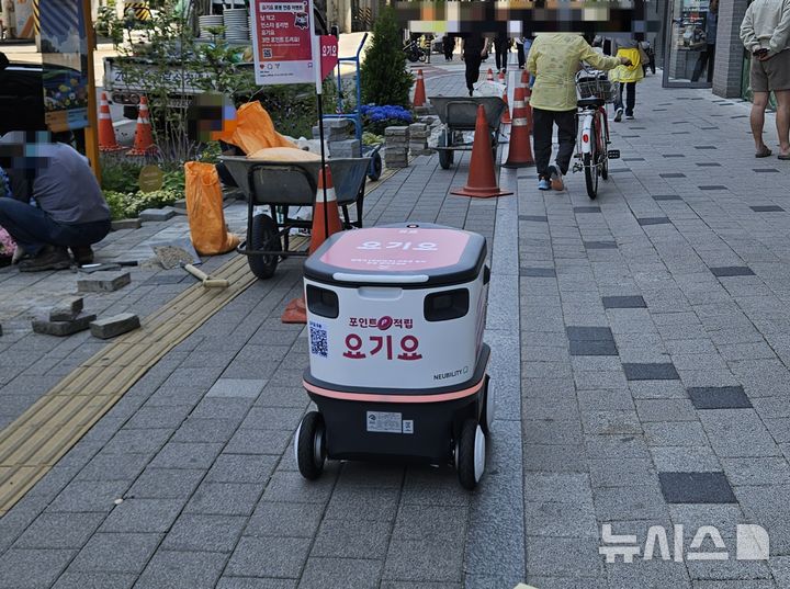 [서울=뉴시스]염지윤 인턴기자= 공사장 인근에 세워전 안전콘을 피해 주행하는 요기요 배달로봇의 모습. 2026.05.13