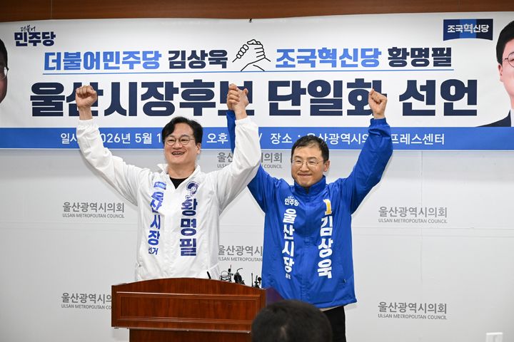 [울산=뉴시스] 6·3 지방선거 후보 등록이 시작된 14일 조국혁신당 황명필 울산시장 예비후보(왼쪽)가 더불어민주당 김상욱 후보와의 단일화에 전격 합의한 가운데 이날 오후 울산시의회 프레스센터에서 두 후보가 손을 맞잡고 있다. (사진=울산시의회 제공) 2026.05.14. photo@newsis.com *재판매 및 DB 금지
