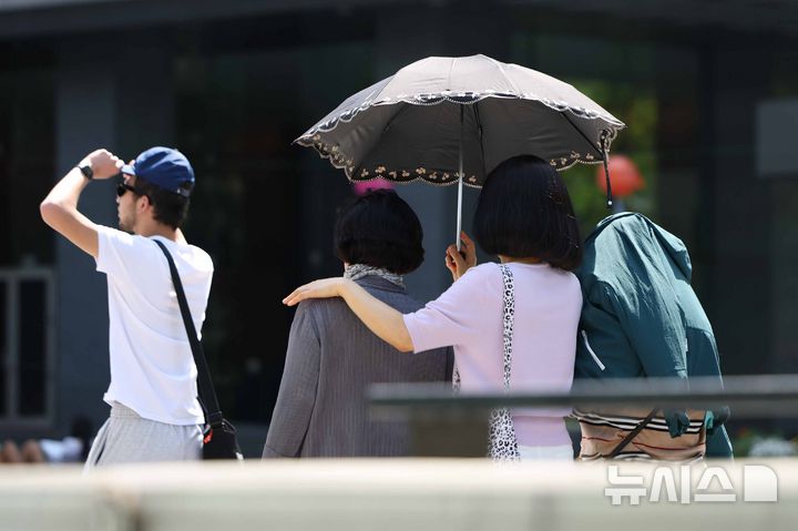 [서울=뉴시스] 김명년 기자 = 초여름 날씨를 보인 14일 오후 서울 종로구 광화문광장에서 시민이 양산을 쓰고 이동하고 있다. 2026.05.14. kmn@newsis.com
