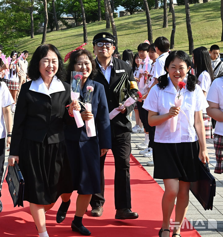[수원=뉴시스] 김종택기자 = 스승의날인 15일 경기 수원시 팔달구 매향중학교에서 열린 '추억의 책가방' 행사에서 교복을 입은 선생님들이 학생들의 축하와 응원속에 레드카펫을 밟으며 행진하고 있다. 2026.05.15. jtk@newsis.com