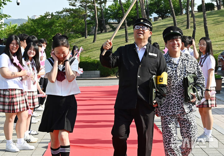 [수원=뉴시스] 김종택기자 = 스승의날인 15일 경기 수원시 팔달구 매향중학교에서 열린 '추억의 책가방' 행사에서 교복을 입은 선생님들이 학생들의 축하와 응원속에 레드카펫을 밟으며 행진하고 있다. 2026.05.15. jtk@newsis.com