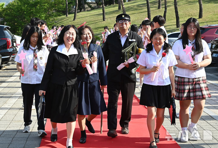 [수원=뉴시스] 김종택기자 = 스승의날인 15일 경기 수원시 팔달구 매향중학교에서 열린 '추억의 책가방' 행사에서 교복을 입은 선생님들이 학생들의 축하와 응원속에 레드카펫을 밟으며 행진하고 있다. 2026.05.15. jtk@newsis.com