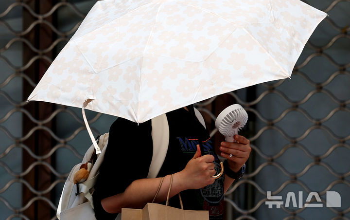 [대구=뉴시스] 이무열 기자 = 대구 낮 최고기온이 30도까지 오르며 초여름 날씨를 보인 15일 대구 중구 동성로에서 한 시민이 양산과 손 선풍기를 들고 이동하고 있다. 2026.05.15. lmy@newsis.com