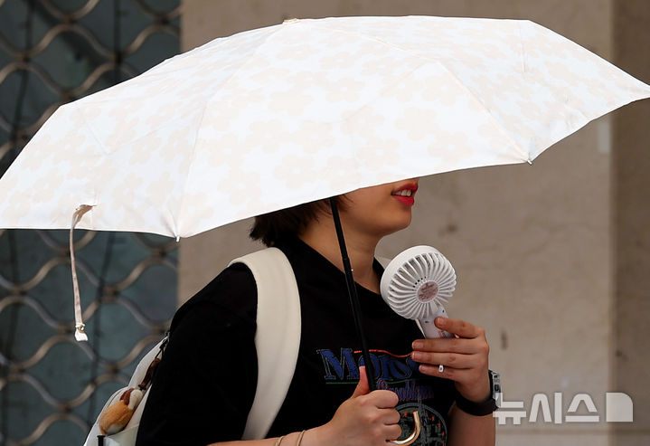 [대구=뉴시스] 이무열 기자 = 대구 낮 최고기온이 30도까지 오르며 초여름 날씨를 보인 15일 대구 중구 동성로에서 한 시민이 양산과 손 선풍기를 들고 이동하고 있다. 2026.05.15. lmy@newsis.com