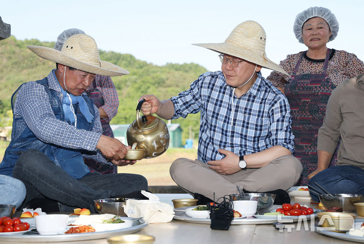 [대구=뉴시스] 최동준 기자 = 이재명 대통령이 15일 대구 군위군 소보면 마을 일원에서 모내기 작업을 마친 뒤 주민들과 '새참 간담회'를 하고 있다. (청와대통신사진기자단) 2026.05.15. photocdj@newsis.com