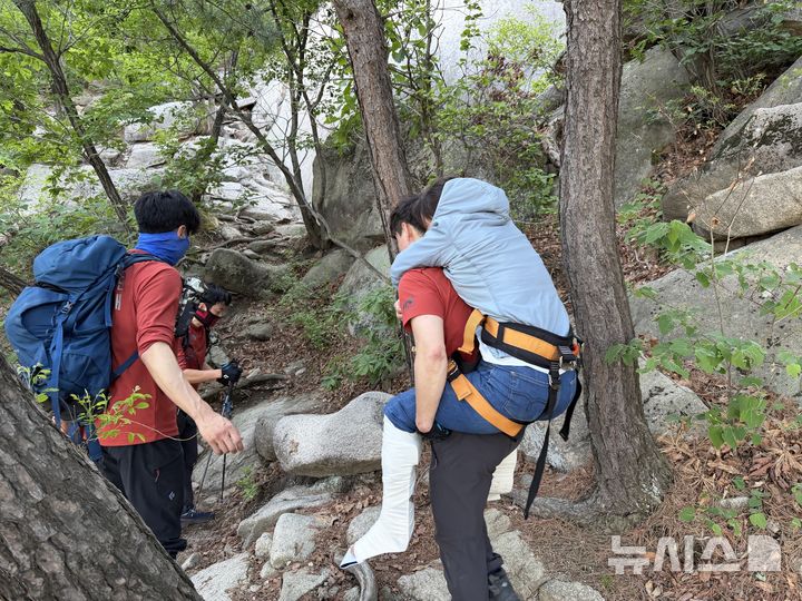 [서울=뉴시스]4일 오후 구조 출동 지령을 받은 북한산 산악구조대 대원들이 족두리봉 하단에서 실족한 여성을 업고 하산하고 있다. (사진=북한산 산악구조대 제공) 2026.05.04. photo@newsis.com