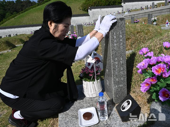 [광주=뉴시스] 이현행 기자 = 제46주년 5·18민주화운동 기념식 하루를 앞둔 17일 오전 광주 북구 운정동 국립5·18민주묘지에서 고(故) 김영두 열사의 누나 김영화(74) 여사가 묘비를 쓰다듬으며 눈물을 흘리고 있다. 2026.05.17. lhh@newsis.com