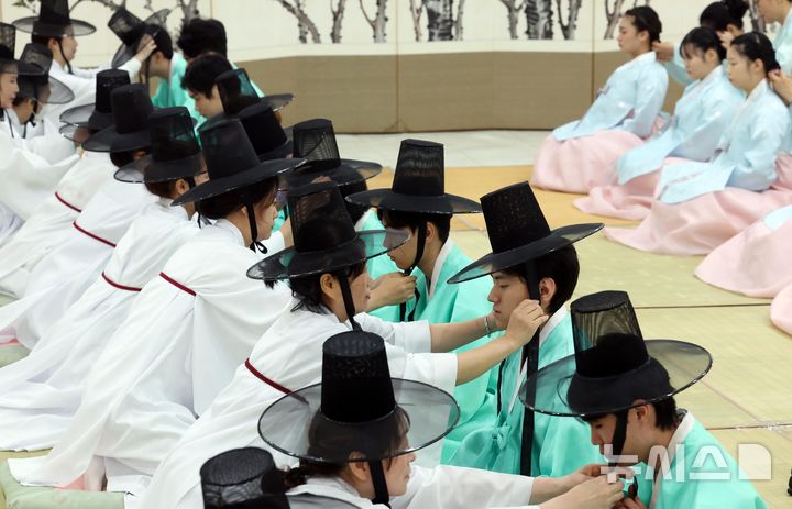  [부산=뉴시스] 하경민 기자 = 제54회 성년의 날인 18일 부산 사상구 부산시여성문화회관 대강당에서 열린 '전통 성년례'에 참가한 남녀 성년자들이 갓을 쓰고 비녀를 꽂는 의식인 관례와 계례를 하고 있다. 2026.05.18. yulnetphoto@newsis.com
