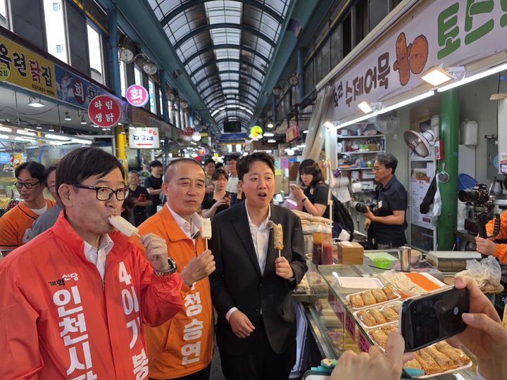 [인천=뉴시스] 전예준 기자 = 개혁신당 이기붕(맨 왼쪽) 인천시장 후보와 정승연 연수갑 후보, 이준석 대표가 19일 인천 연수구 옥련시장을 찾아 어묵을 먹고 있다. 2026.05.19. kok@newsis.com&nbsp; *재판매 및 DB 금지