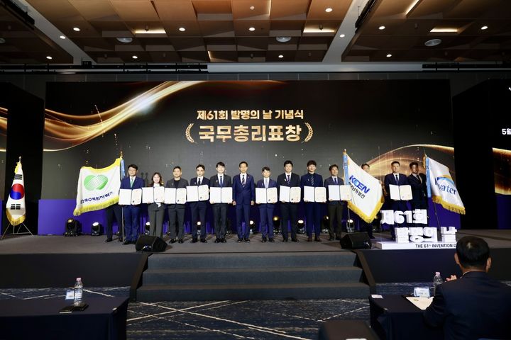[세종=뉴시스]발명의날 수상자 단체사진이다. 수상자 김군회 KOEN연구소장, 한국남동발전 깃발 좌측.(사진=한국남동발전 제공) *재판매 및 DB 금지