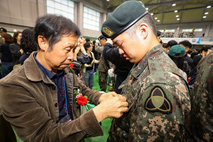 [임실=뉴시스] 20일 전북 임실군 제35보병사단 김범수관에서 진행된 신병수료식에서 신진욱 이병의 아버지(왼쪽)가 인식표를 신 이병의 목에 걸어준 후 계급장을 달아주고 있다. (사진=제35보병사단 제공) 2026.05.20. photo@newsis.com *재판매 및 DB 금지