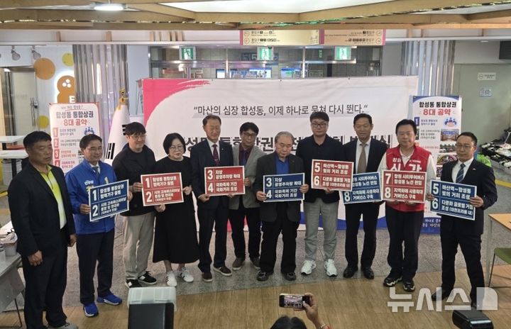 [창원=뉴시스]20일 오후 경남 창원시 마산회원구 합성동 대현프리몰 트리스퀘어에서 열린 '합성동 통합상권발전위원회 출범식'에 참석한 윤상수(왼쪽서 여섯 번째) 회장과 상인회장, 손태화 창원시의회 의장, 국민의힘 강기윤·더불어민주당 송순호 창원시장 후보 등이 통합상권발전위 요구사항이 적힌 손피켓을 들고 기념촬영하고 있다.(사진=합성동 통합상권발전위 제공) 2026.05.20. photo@newsis.com