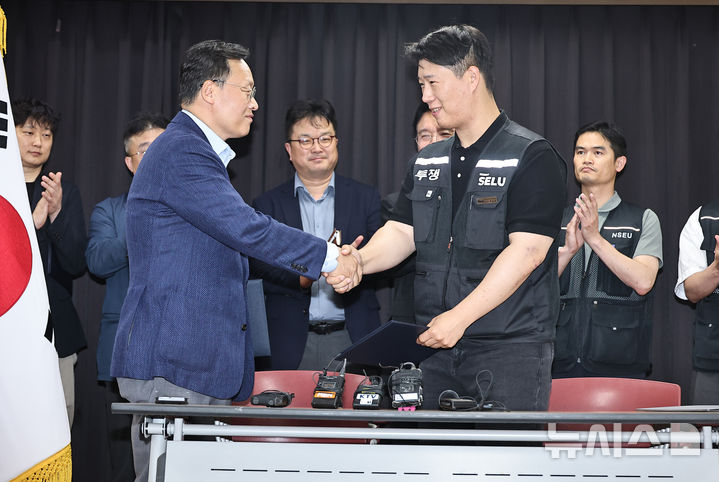 [수원=뉴시스] 김종택기자 = 20일 경기도 수원시 장안구 경기고용노동청에서 열린 삼성전자 임금협상을 마친 후 여명구 삼성전자 DS(디바이스솔루션·반도체 사업 담당) 피플팀장과 최승호 삼성그룹 초기업노동조합 삼성전자지부 위원장이 잠정 합의한에 서명한 후 손을 맞잡고 있다. 2026.05.20. photo@newsis.com
