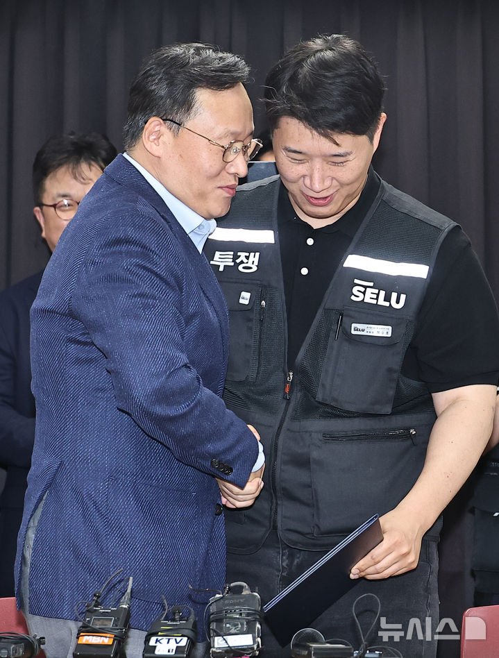 [수원=뉴시스] 김종택기자 = 20일 경기도 수원시 장안구 경기고용노동청에서 열린 삼성전자 임금협상을 마친 후 여명구 삼성전자 DS(디바이스솔루션·반도체 사업 담당) 피플팀장과 최승호 삼성그룹 초기업노동조합 삼성전자지부 위원장이 잠정 합의한에 서명한 후 손을 맞잡고 있다. 2026.05.20. photo@newsis.com