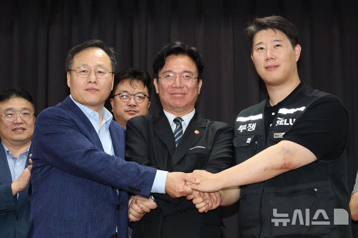 [수원=뉴시스] 김종택기자 = 20일 경기 수원시 장안구 경기고용노동청에서 열린 삼성전자 임금협상을 마친 후 여명구 삼성전자 DS(디바이스솔루션·반도체 사업 담당) 피플팀장(왼쪽부터)과 김영훈 고용노동부 장관, 최승호 삼성그룹 초기업노동조합 삼성전자지부 위원장이 잠정 합의한에 서명한 후 손을 맞잡고 있다. (공동취재) 2026.05.20. photo@newsis.com