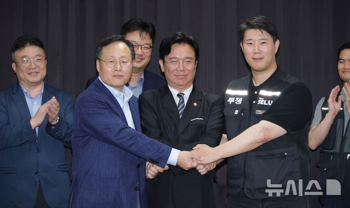 [수원=뉴시스] 김종택기자 = 20일 경기도 수원시 장안구 경기고용노동청에서 열린 삼성전자 임금협상을 마친 후 여명구 삼성전자 DS(디바이스솔루션·반도체 사업 담당) 피플팀장과 김영훈 고용노동부 장관, 최승호 삼성그룹 초기업노동조합 삼성전자지부 위원장이 잠정 합의한에 서명한 후 손을 맞잡고 있다. (공동취재) 2026.05.20. photo@newsis.com
