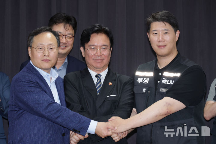 [수원=뉴시스] 20일 경기도 수원시 장안구 경기고용노동청에서 열린 삼성전자 임금협상을 마친 후 여명구 삼성전자 DS(디바이스솔루션·반도체 사업 담당) 피플팀장과 김영훈 고용노동부 장관, 최승호 삼성그룹 초기업노동조합 삼성전자지부 위원장이 잠정 합의한에 서명한 후 손을 맞잡고 있다. (공동취재) 2026.05.20. photo@newsis.com
