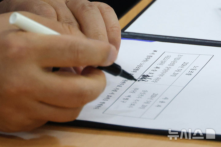 [수원=뉴시스] 김종택기자 = 여명구 삼성전자 DS(디바이스솔루션·반도체 사업 담당) 피플팀장이 20일 오후 경기 수원시 장안구 경기지방고용노동청에서 열린 삼성전자 노사교섭 결과 브리핑에서 합의안에 서명을 하고 있다. (공동취재) 2026.05.20. photo@newsis.com
