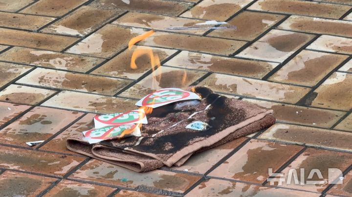 [광주=뉴시스] 광주·전남 143개 시민단체로 이뤄진 스타벅스 코리아 역사왜곡 사태 규탄 참가자 일동이 21일 광주 서구 이마트 상무점 앞에서 기자회견을 열어 스타벅스를 향한 불매운동을 촉구한 가운데 불이 붙은 스타벅스 수건이 타고 있다. (사진 = 독자 제공) 2026.05.21. photo@newsis.com