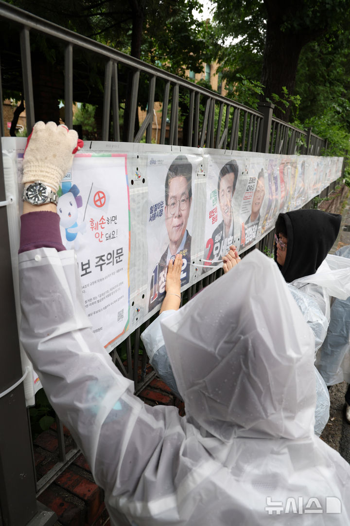 [서울=뉴시스] 전신 기자 = 21일 서울 종로구 예술가의 집 담장에서 서울시선관위 직원들이 제9회 전국동시지방선거 선거벽보를 부착하고 있다. 2026.05.21. photo1006@newsis.com