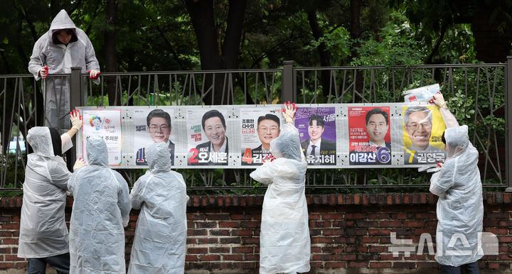 [서울=뉴시스] 전신 기자 = 21일 서울 종로구 예술가의 집 담장에서 서울시선관위 직원들이 제9회 전국동시지방선거 선거벽보를 부착하고 있다. 2026.05.21. photo1006@newsis.com