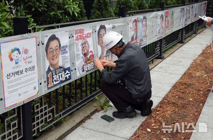  [부산=뉴시스] 하경민 기자 = 21일 부산 연제구의 한 거리에서 선거벽보 제작업체 관계자들이 건물 담장에 선거벽보를 부착하고 있다. 부산시선거관리위원회는 제9회 전국동시지방선거와 국회의원 부산 북구갑 보궐선거 후보자의 선거벽보를 부산 내 1750여 곳에 부착한다. 2026.05.21. yulnetphoto@newsis.com