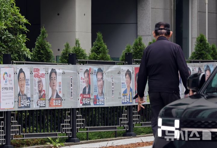  [부산=뉴시스] 하경민 기자 = 21일 부산 연제구의 한 거리에서 시민이 담장에 부착된 선거벽보를 보고 있다. 2026.05.21. yulnetphoto@newsis.com