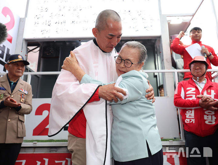 [부산=뉴시스] 김진아 기자 = 제9회 전국동시지방선거 및 국회의원 재·보궐선거의 공식 선거운동이 시작된 21일 박민식 국민의힘 부산 북구갑 국회의원 보궐선거 후보가 부산 북구 구포시장 앞에서 열린 출정식에서 삭발을 한 뒤 자신의 어머니를 안고 있다. 2026.05.21. bluesoda@newsis.com