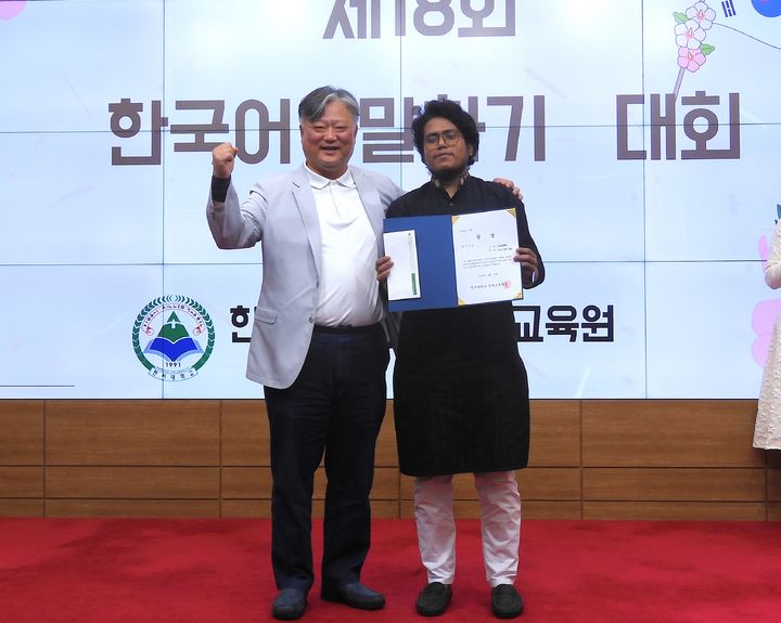 [서산=뉴시스] 가지 자만 호싸인(오른쪽)이 지난 21일 한서대 자악관 국제회의장에서 열린 한국어말하기대회 최우수상을 받은 뒤 김진우 어학교육원장과 기념 사진을 찍고 있다. (사진=한서대학교 제공) 2026.05.22. photo@newsis.com *재판매 및 DB 금지