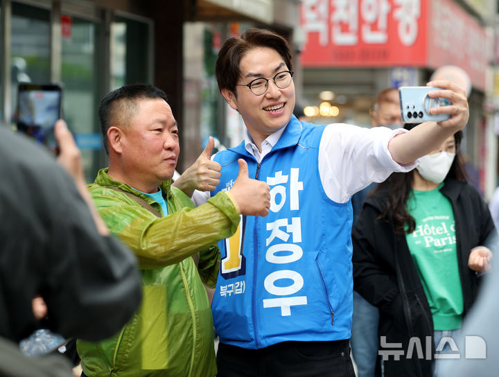[부산=뉴시스] 김진아 기자 = 하정우 더불어민주당 부산 북구갑 국회의원 보궐선거 후보가 22일 부산 북구 만덕대로 일대에서 한 시민과 사진을 찍고 있다. 2026.05.22. bluesoda@newsis.com