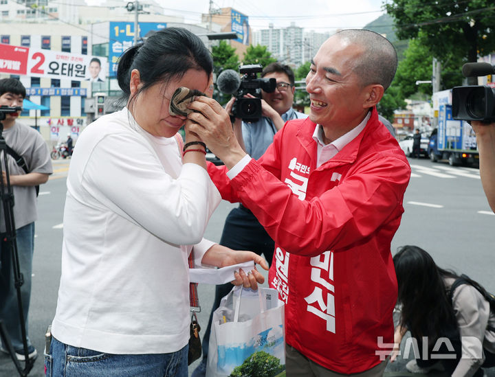 [부산=뉴시스] 김진아 기자 = 박민식 국민의힘 부산 북구갑 국회의원 보궐선거 후보가 22일 부산 북구 신만덕교차로 일대에서 유세를 하던 중 눈물을 흘리는 시민의 응원을 받으며 눈물을 닦아주고 있다. 2026.05.22. bluesoda@newsis.com