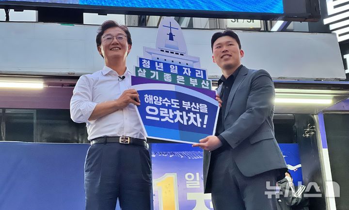 [부산=뉴시스] 원동화 기자 = 전재수 더불어민주당 부산시장 후보가 23일 부산 부산진구 서면 하트조형물 앞에서 대규모 유세를 펼쳤다. 한 청년으로부터 배 피켓을 받았다. 2026.05.23. dhwon@newsis.com