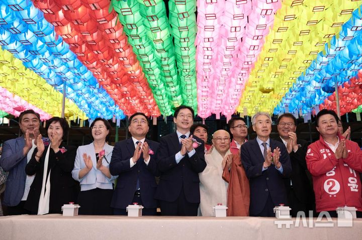 [창원=뉴시스] 지난 23일 밤 경남 창원시 성산구 성주사 봉축법회에 참석한 더불어민주당 김경수(가운데) 경남도지사 후보가 연등에 불이 들어오자 박수를 치고 있다. (사진=김경수후보 선거사무소 제공) 2026.05.24. photo@newsis.com
