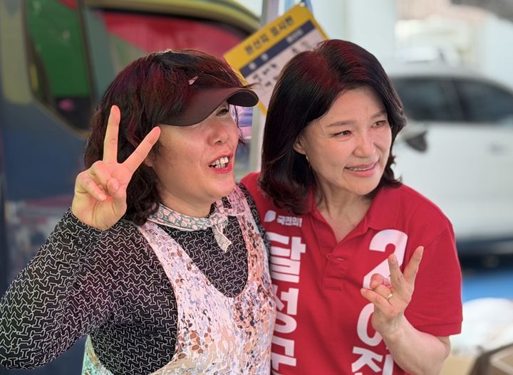 [대구=뉴시스]이진숙 국민의힘 대구 달성군 국회의원 보궐선거 후보가 25일 오후 달성군 현풍도깨비시장에서 가진 유세에서 상인과 포즈를 취하고 있다(사진=이진숙 캠프 제공) 2026.05.25 photo@newsis.com